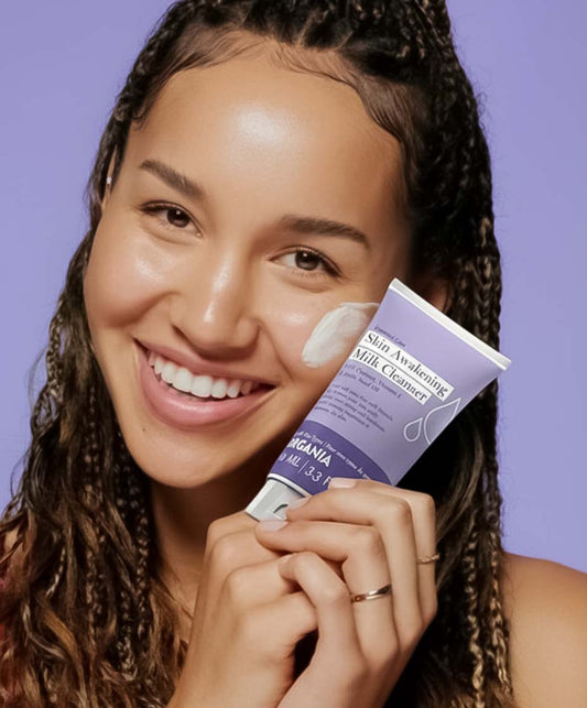 Woman holding a skincare product with a purple background