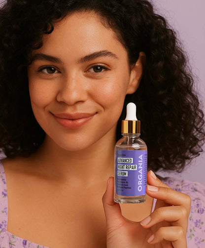 Woman holding a bottle of Organia Advanced Night Repair Serum against a neutral background