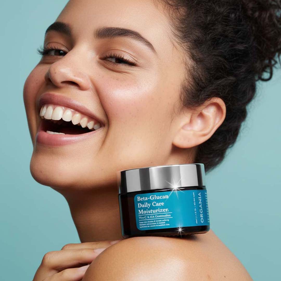 Woman holding a jar of Organia Beta-Glucan Daily Care Moisturizer against a light blue background