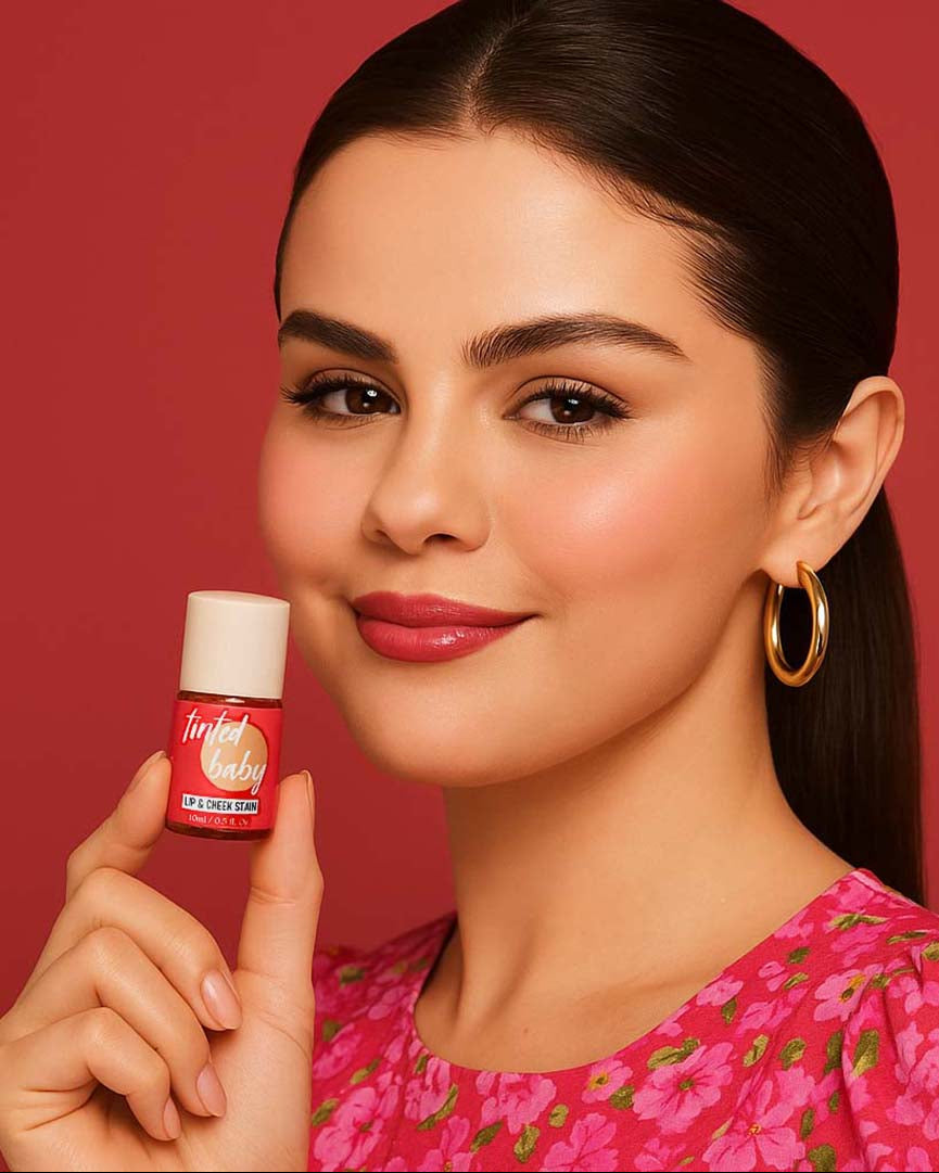 Woman holding a lip and cheek tint bottle with a white cap against a red background